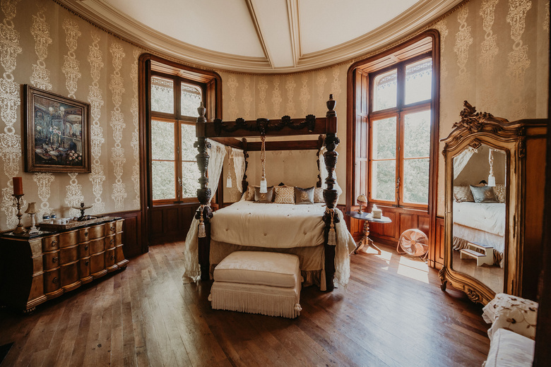 A four-poster bed in a Château Suite with tall windows over the park