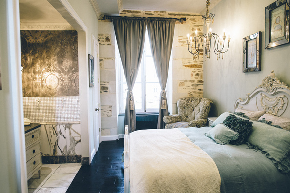 A Coach House Suite with a carved headboard and chandelier